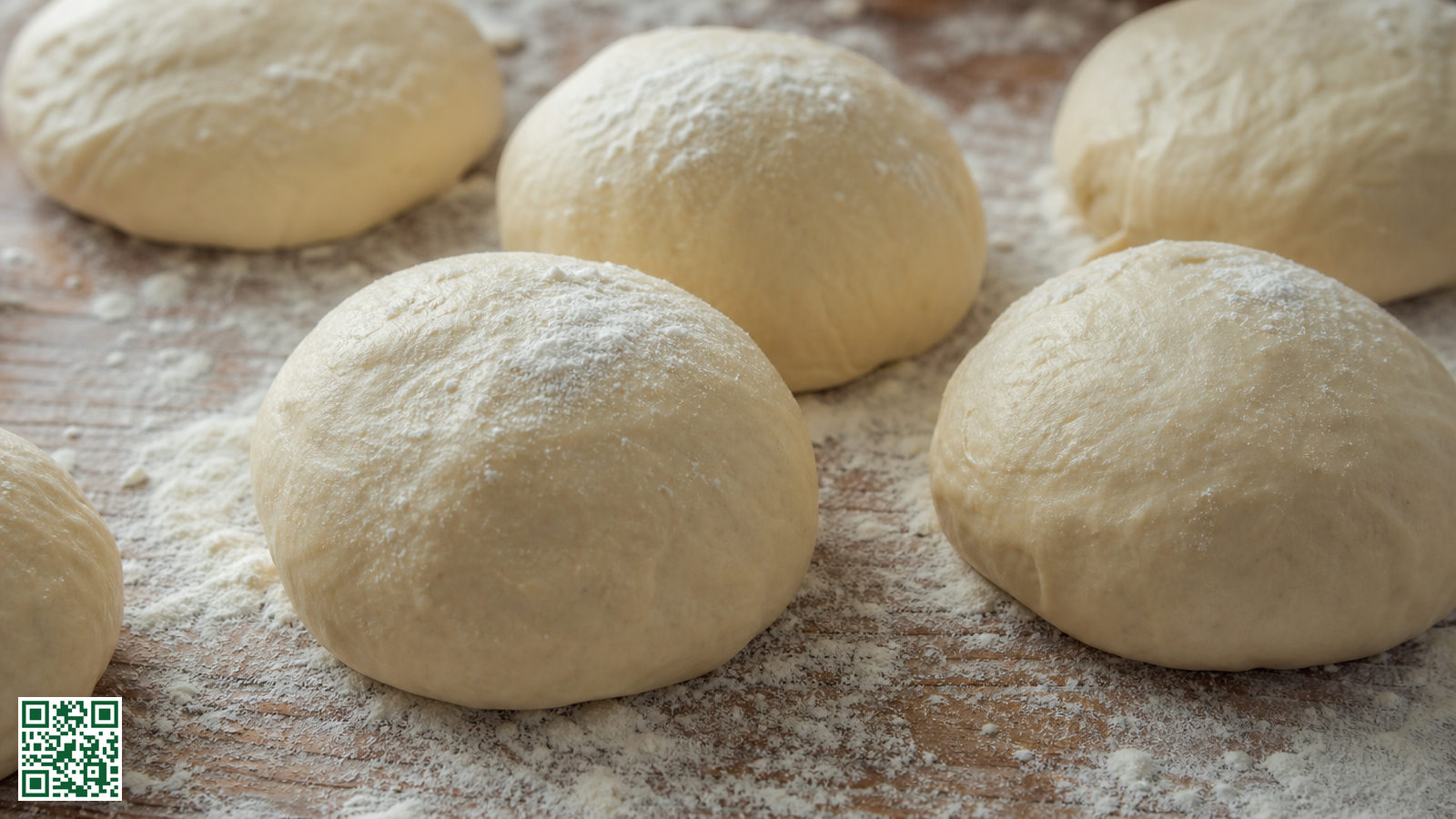 Meerdere deegbollen van verschillend formaat op een bebloemd werkblad