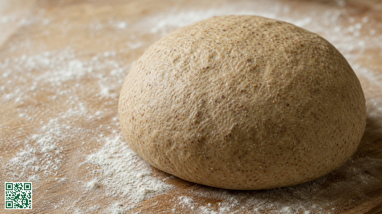 Bol volkoren pizzadeeg met zichtbare zemelen op een bebloemd houten werkblad